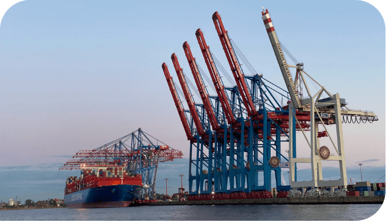 A cargo ship at port next to cranes.