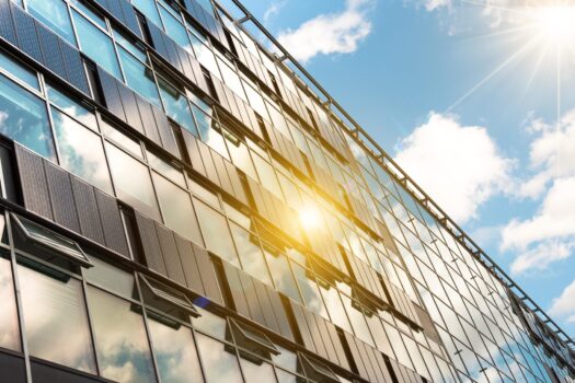solar panels on modern glass facade with sun reflections