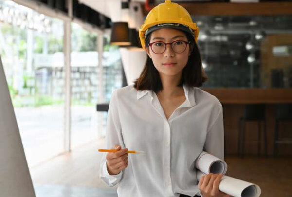 Woman in hardhat with pencil and rolled up paper